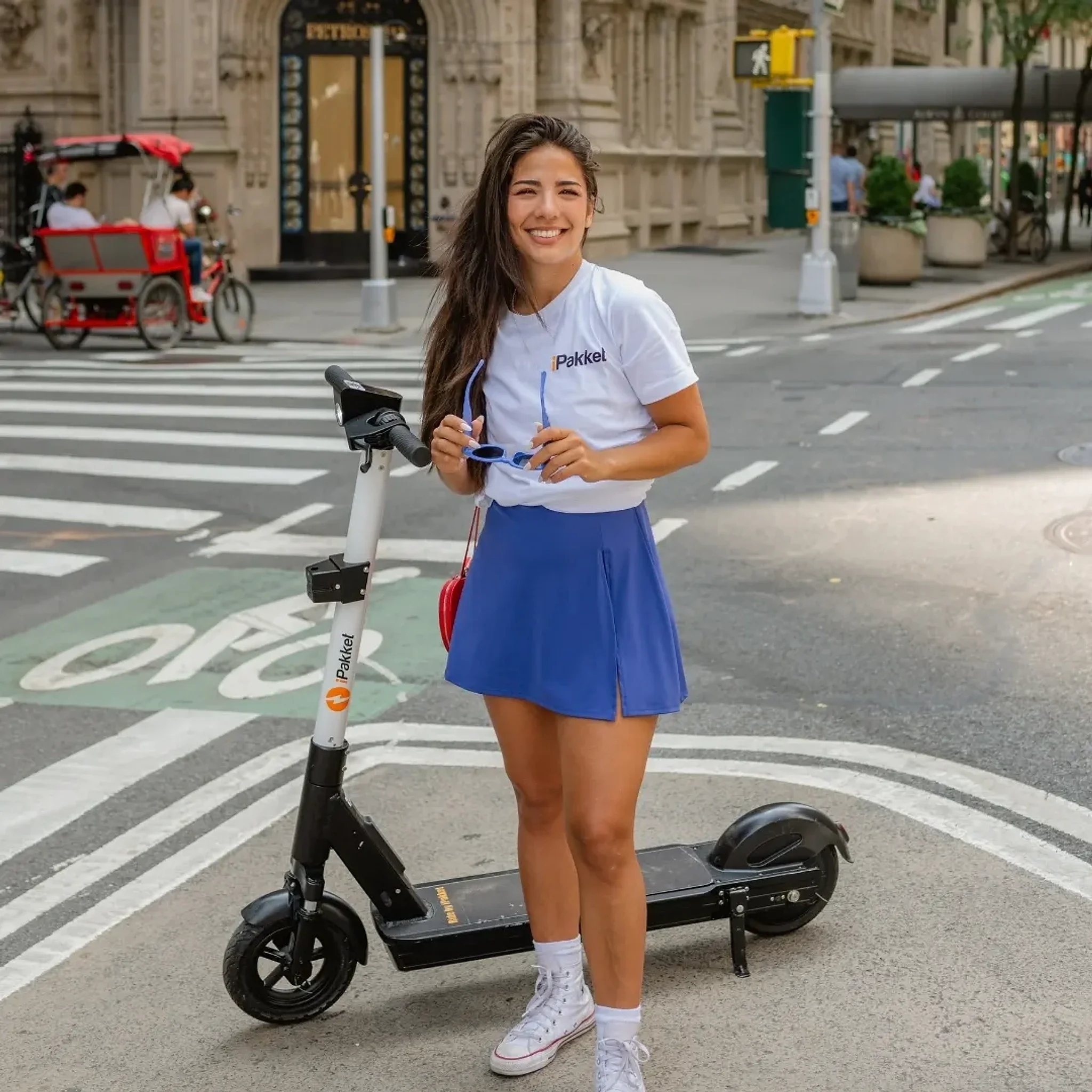 Rider standing with a Ride by iPakket e-scooter at a city crosswalk