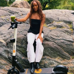Rider relaxing with a smoothie on an e-scooter by the park rocks